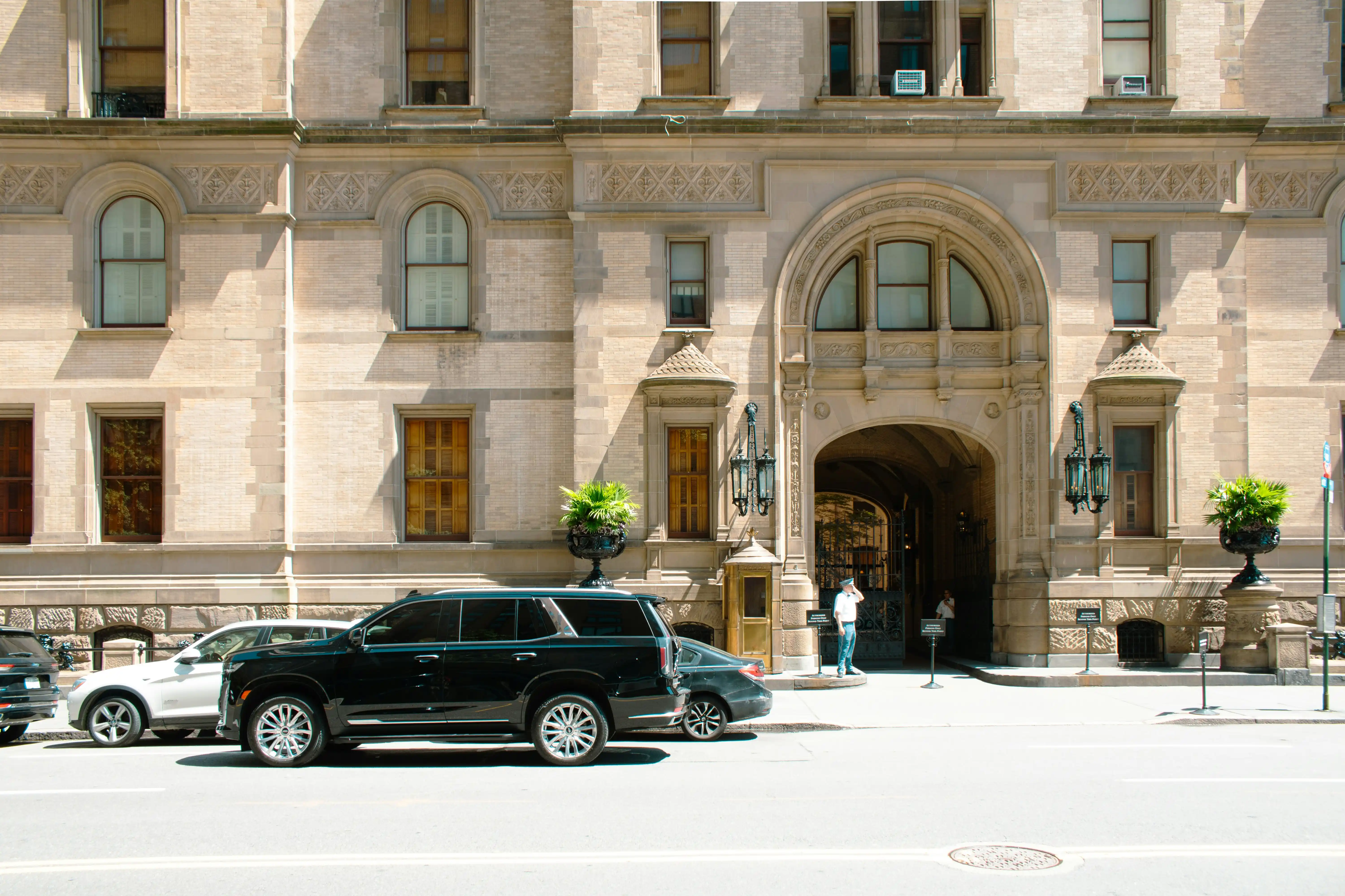 Side-by-side comparison of a black Cadillac Escalade and luxury sedan outside a modern Bellevue hotel, showing relative passenger and luggage capacity